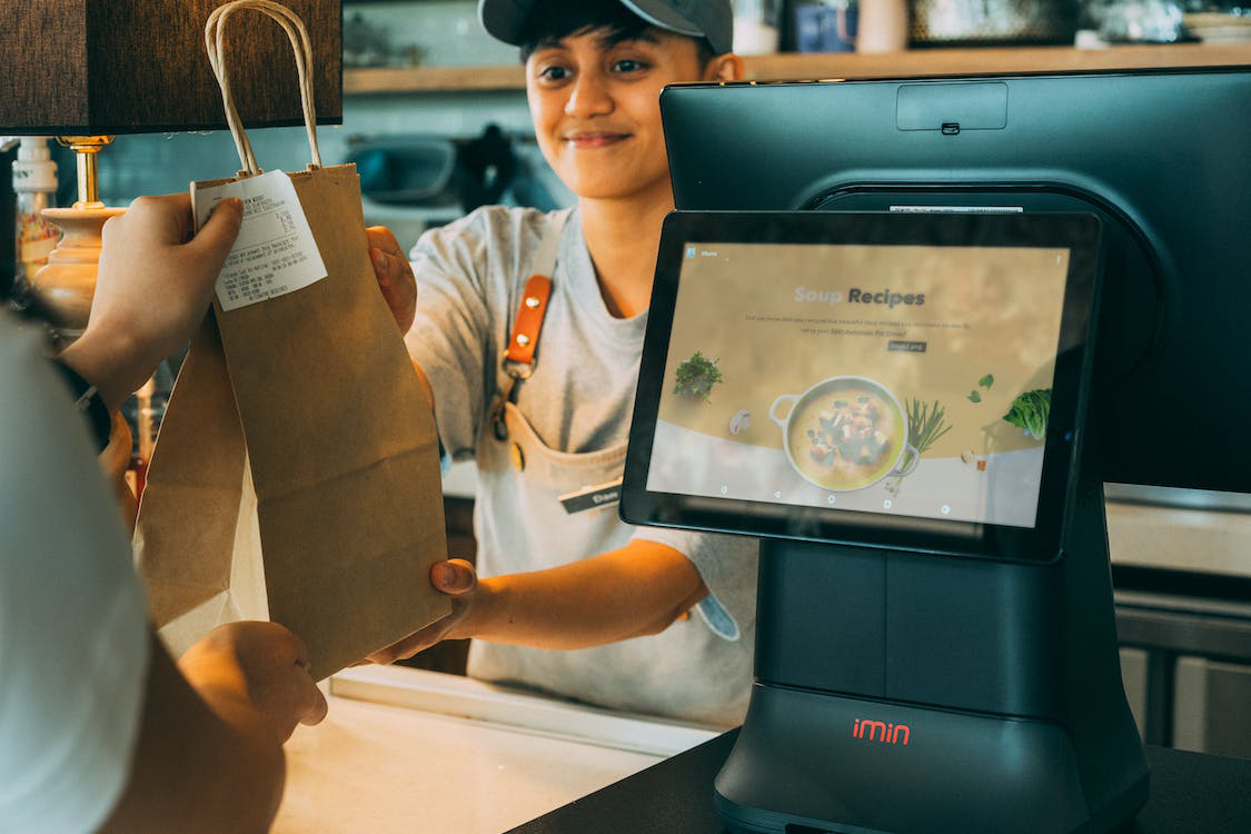 employee handing over a paper bag and receipt to a customer