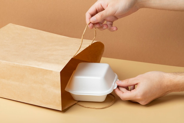 person putting food container in paper packaging