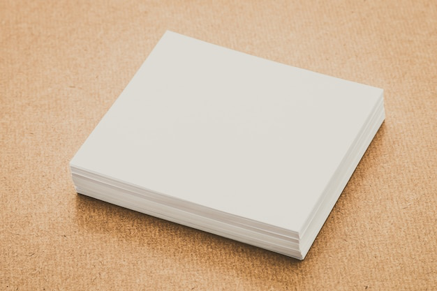 A blank stack of white papers on a brown surface