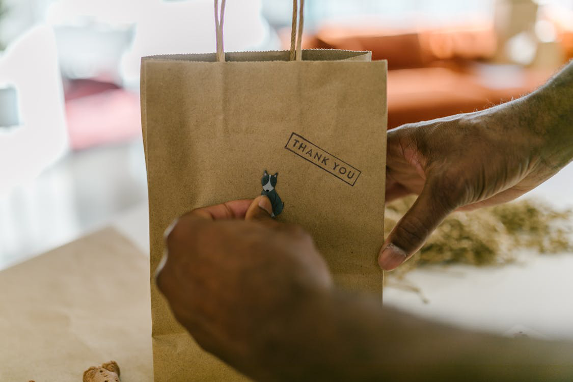 A person putting a dog sticker on a paper bag