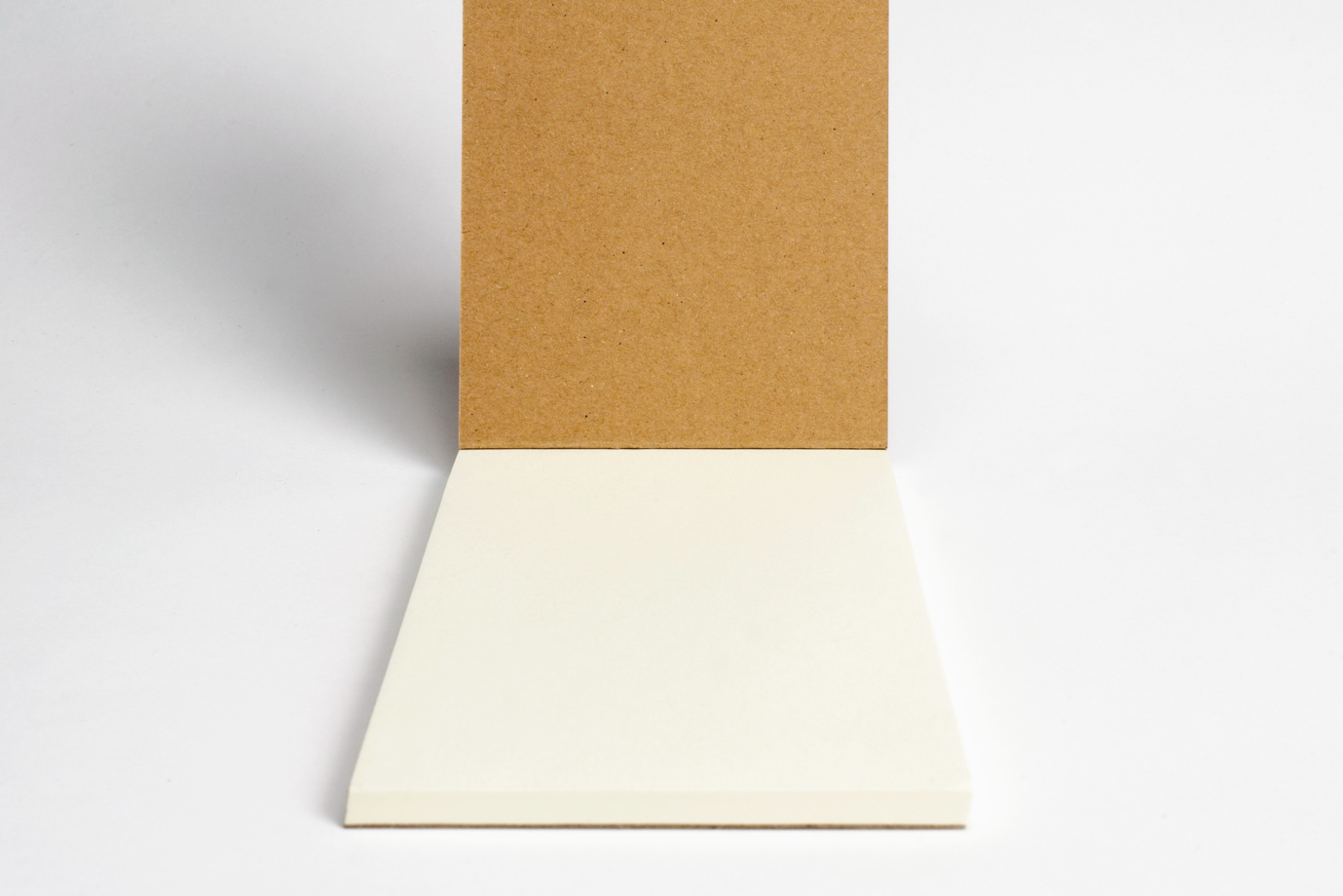 A close-up view of layered duplex board showing the white coated top and grey backing.
