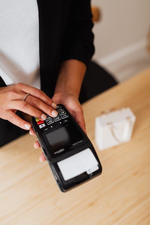 A receipt coming out of a credit card machine in a person’s hand