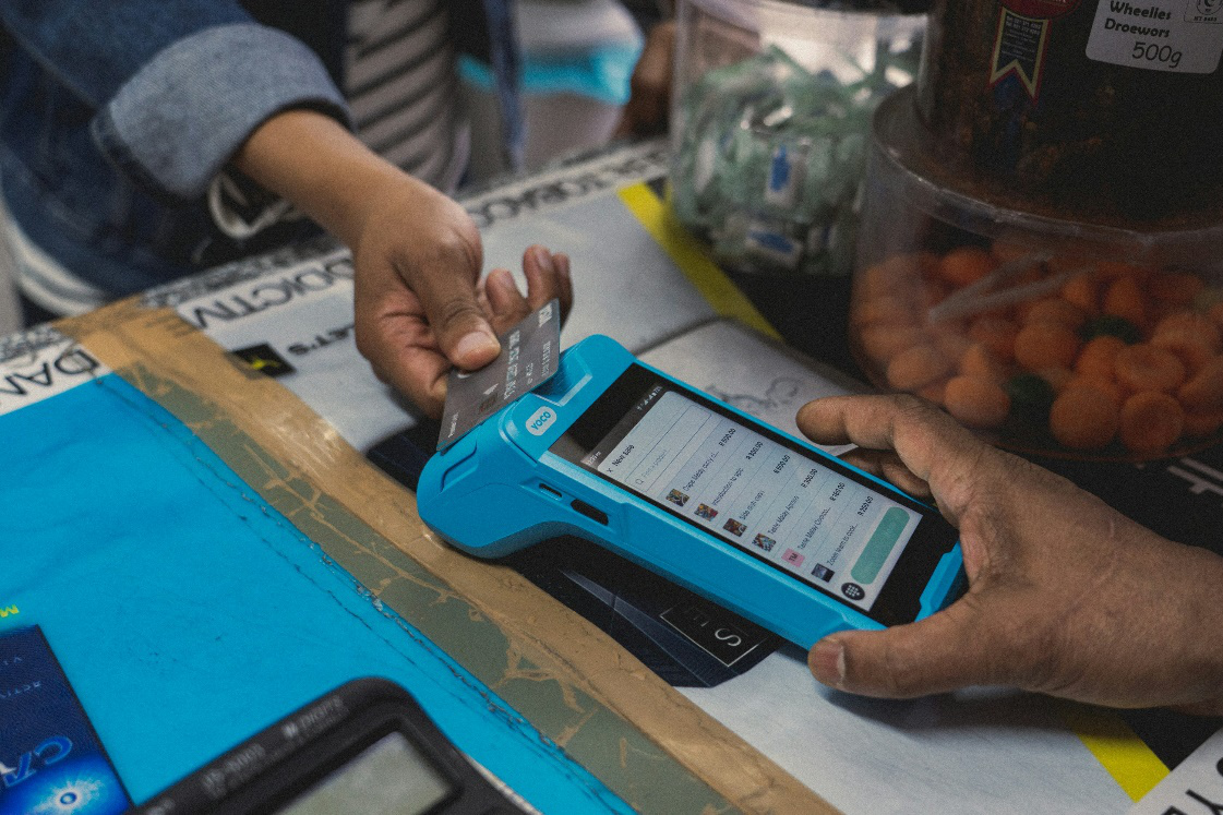 A person using a credit card on a credit card machine at a shop counter